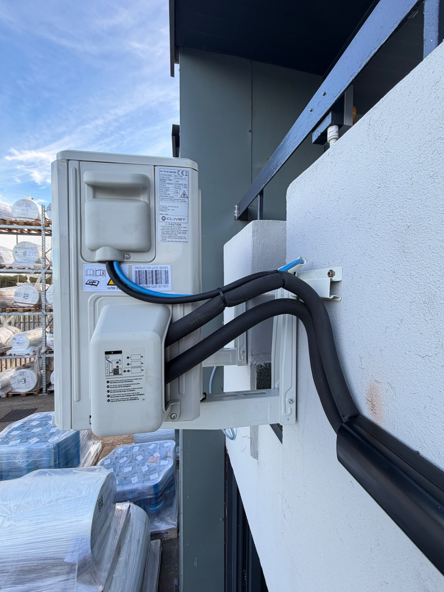 Close-up of a Clivet outdoor unit on a wall bracket showing the pipe connections and black trunking