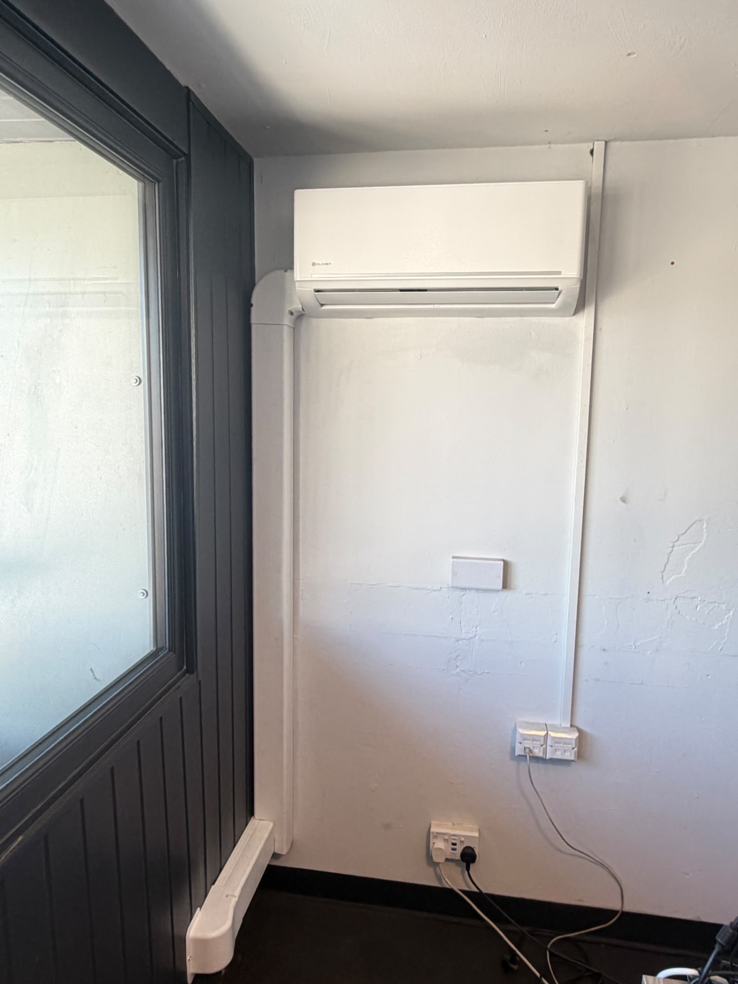 Clivet indoor unit in an office with white internal trunking running down the wall